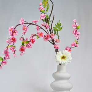 Premium artificial flower arrangement featuring lifelike white gerbera and pink plum blossoms in a sculptural minimalist vase, inspired by Japanese ikebana floral design.