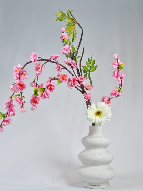 Premium artificial flower arrangement featuring lifelike white gerbera and pink plum blossoms in a sculptural minimalist vase, inspired by Japanese ikebana floral design.